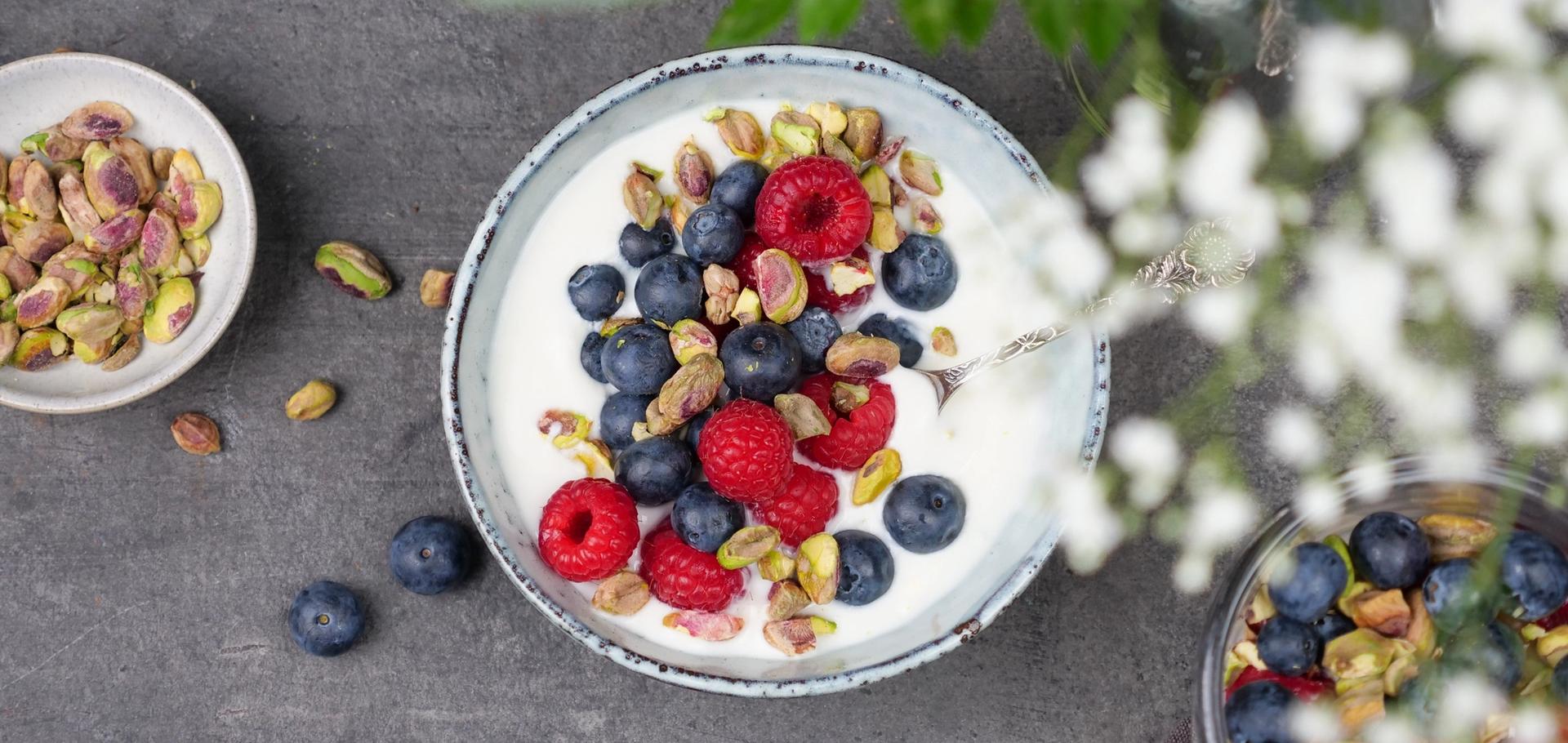 Skål med yoghurt, med bringebær, blåbær og pistasjenøtter