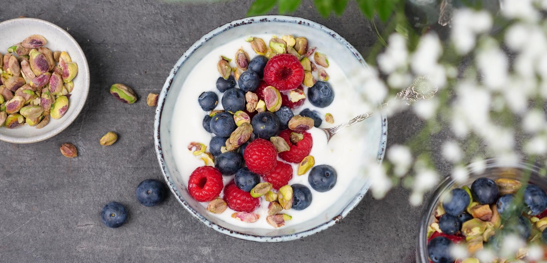 Skål med yoghurt, med bringebær, blåbær og pistasjenøtter
