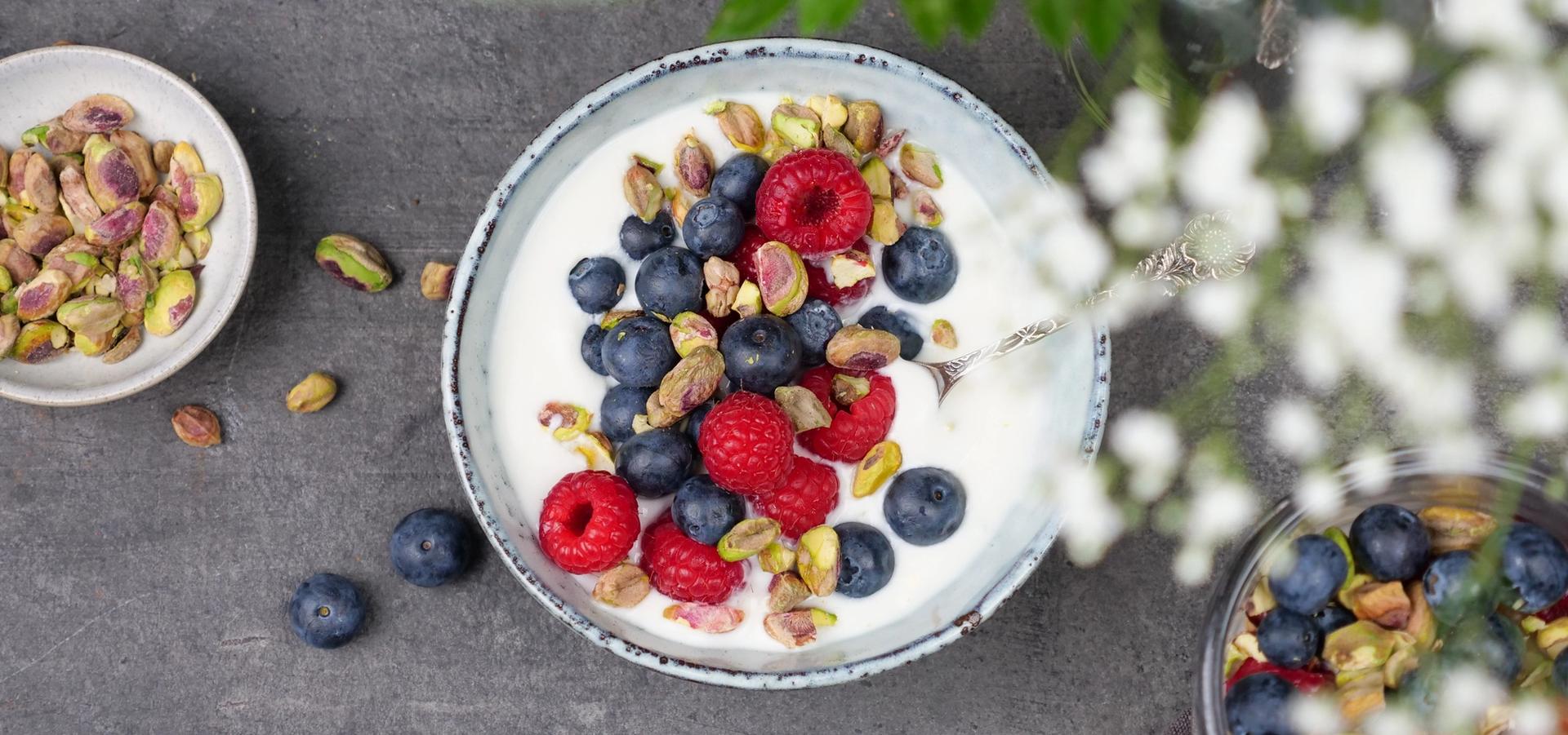 Skål med yoghurt, med bringebær, blåbær og pistasjenøtter