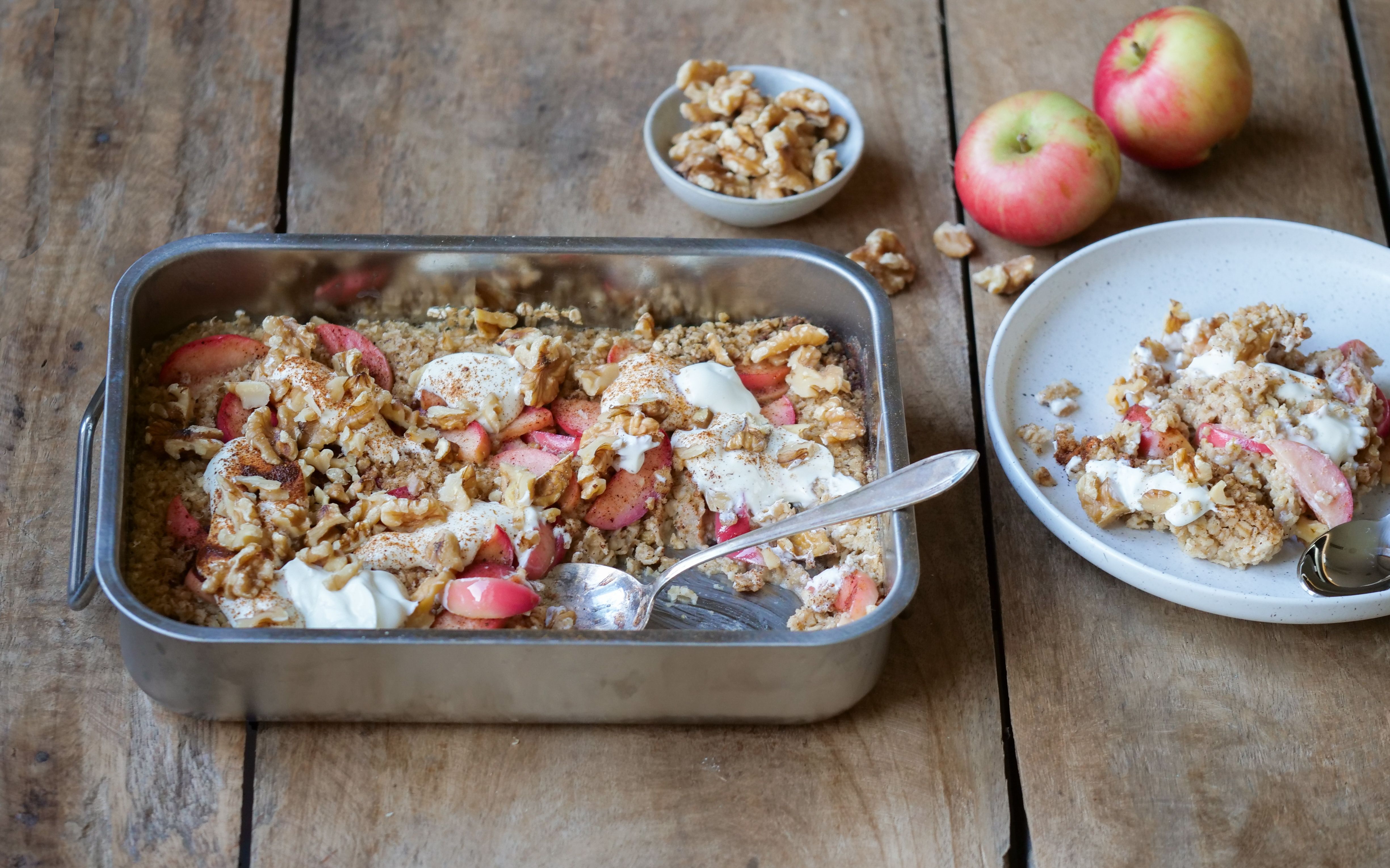 En form med bakt havregrøt toppet med epler, kanel og nøtter 