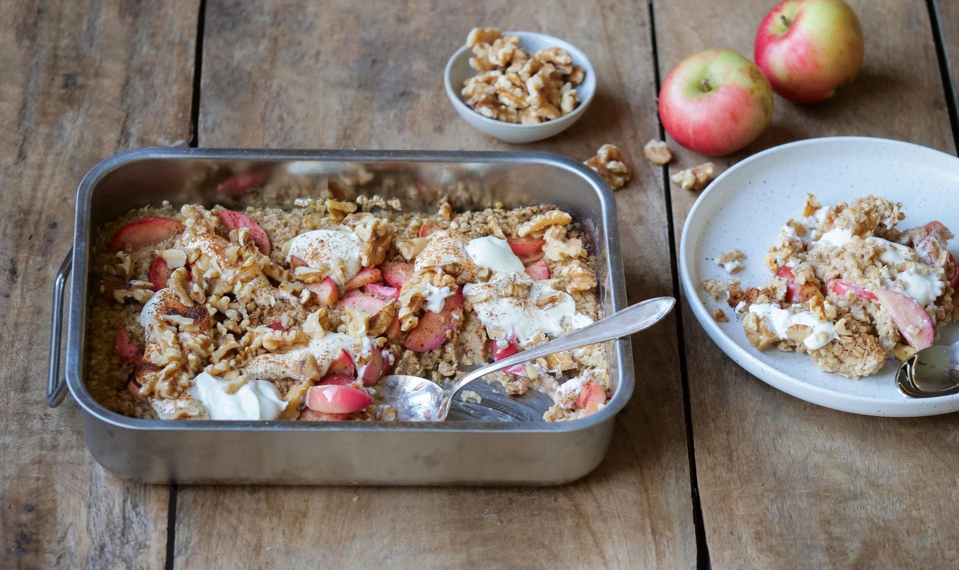 En form med bakt havregrøt toppet med epler, kanel og nøtter
