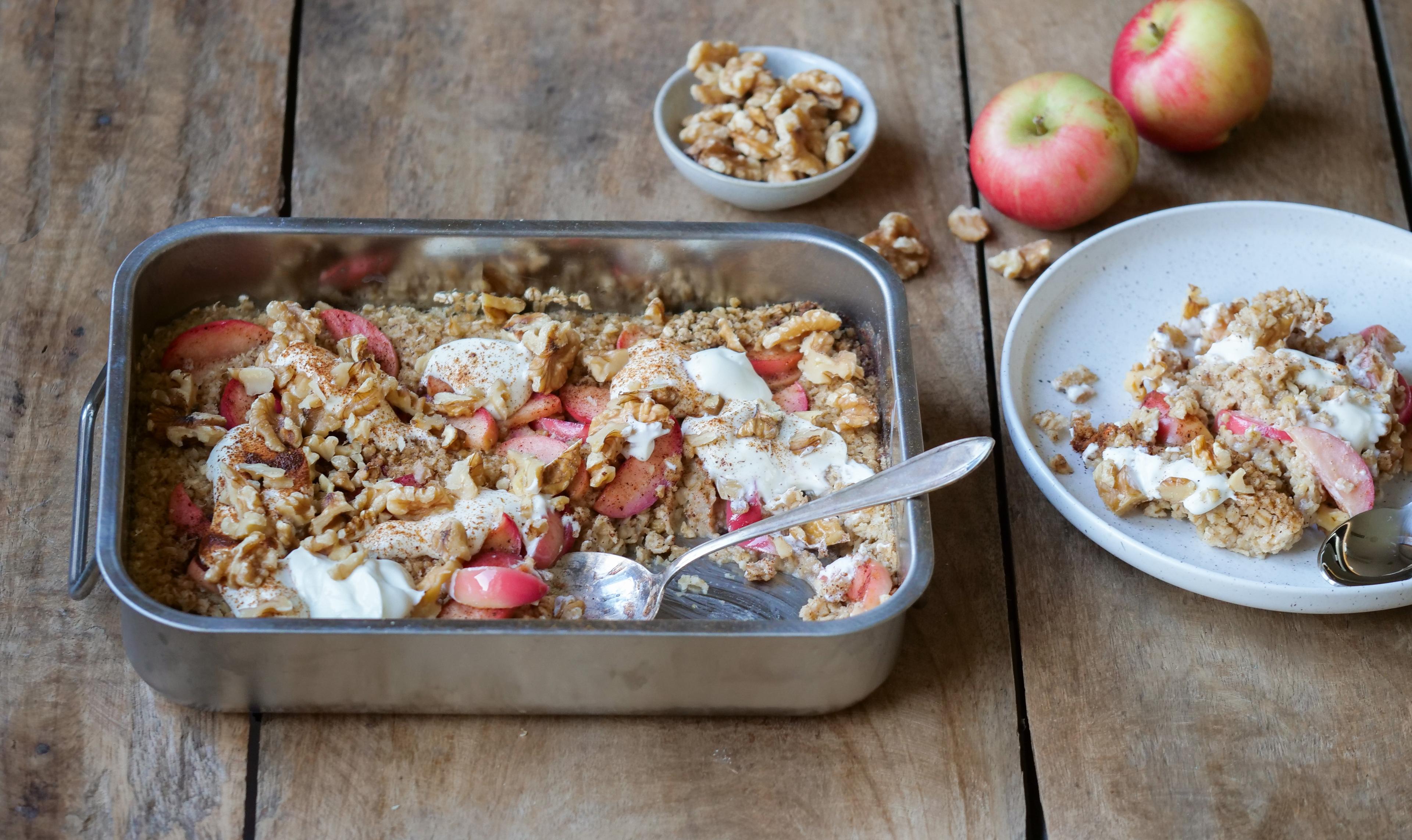 En form med bakt havregrøt toppet med epler, kanel og nøtter