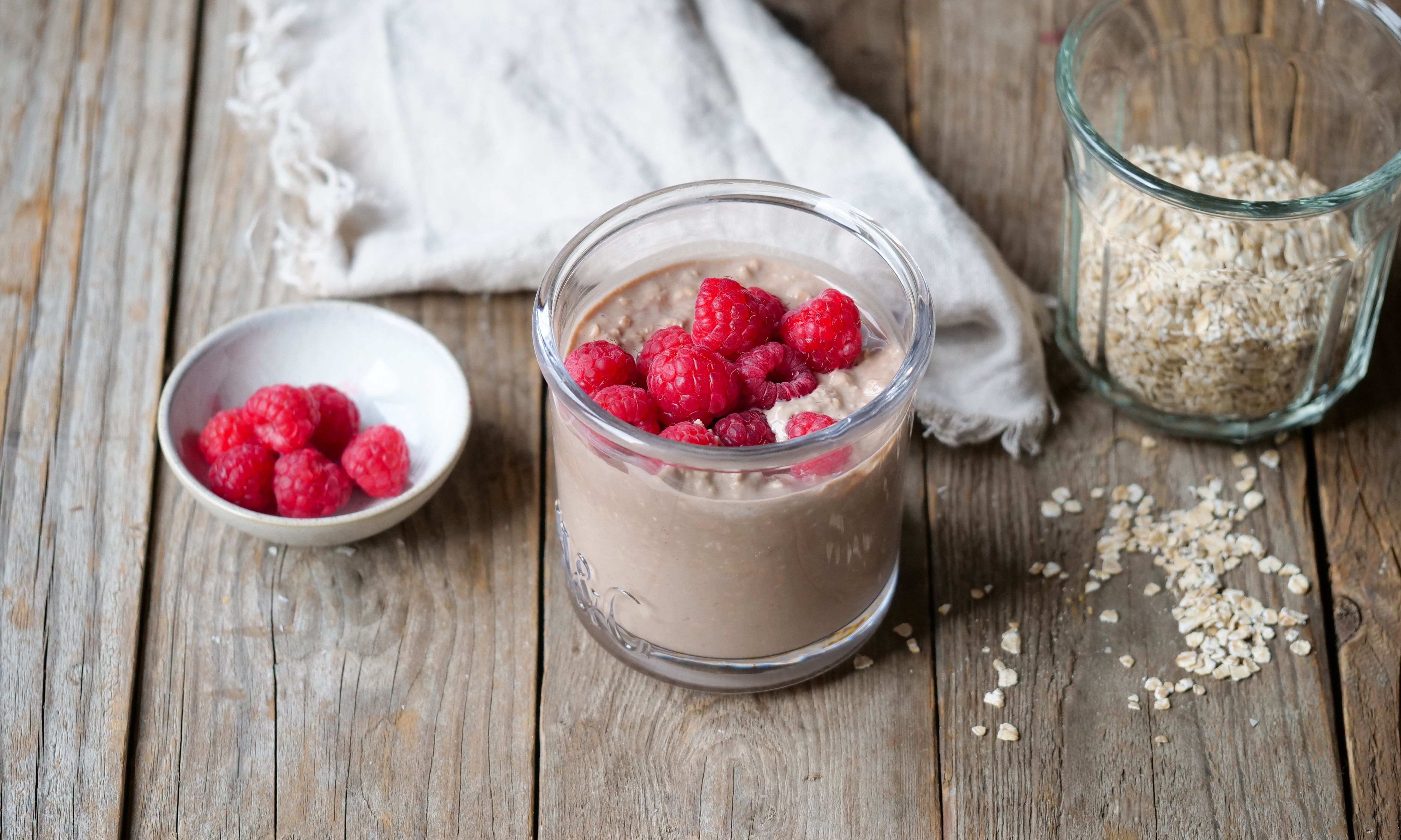 Et glass med kjøleskapsgrøt toppet  med bringebær