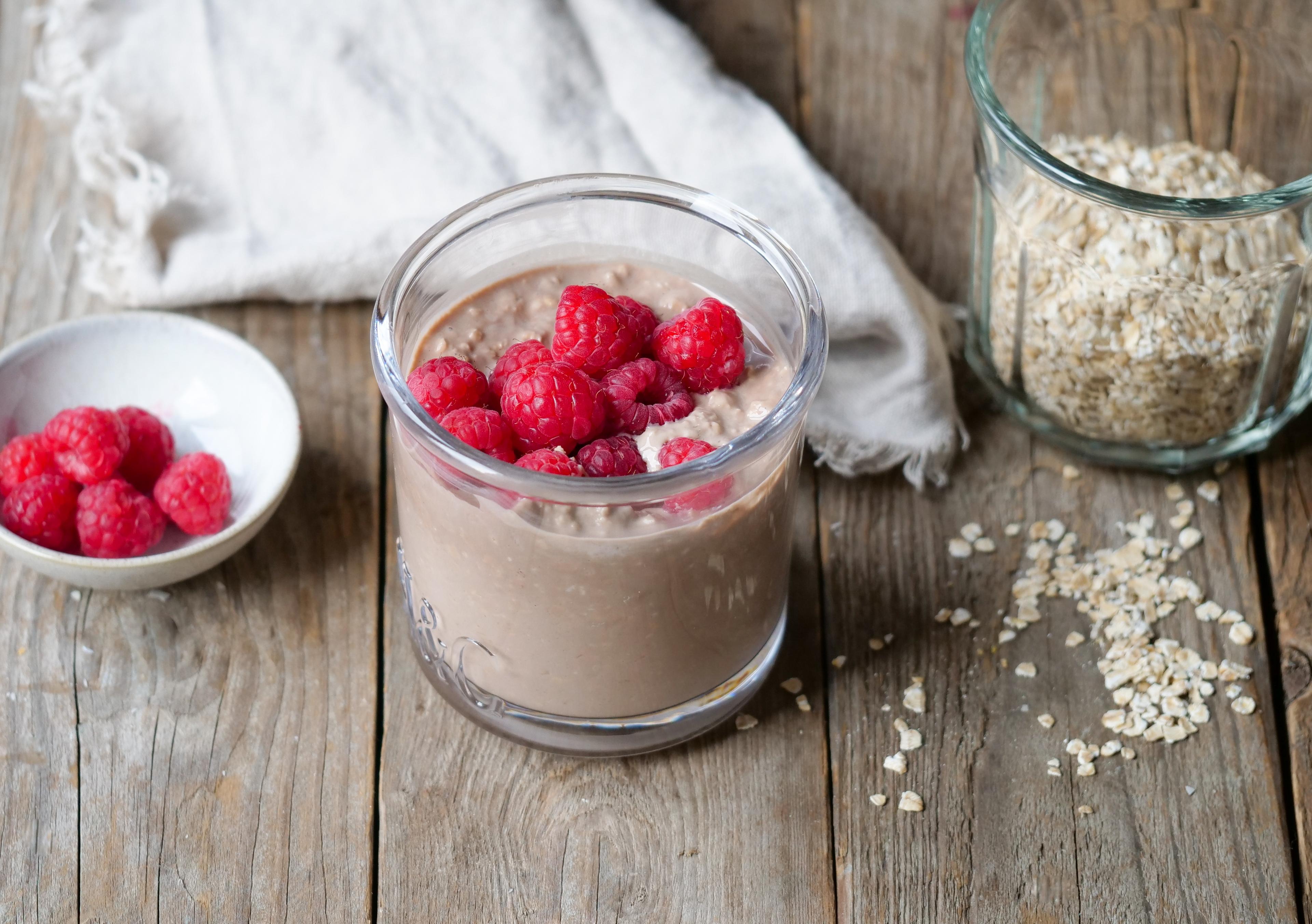 Et glass med kjøleskapsgrøt toppet  med bringebær