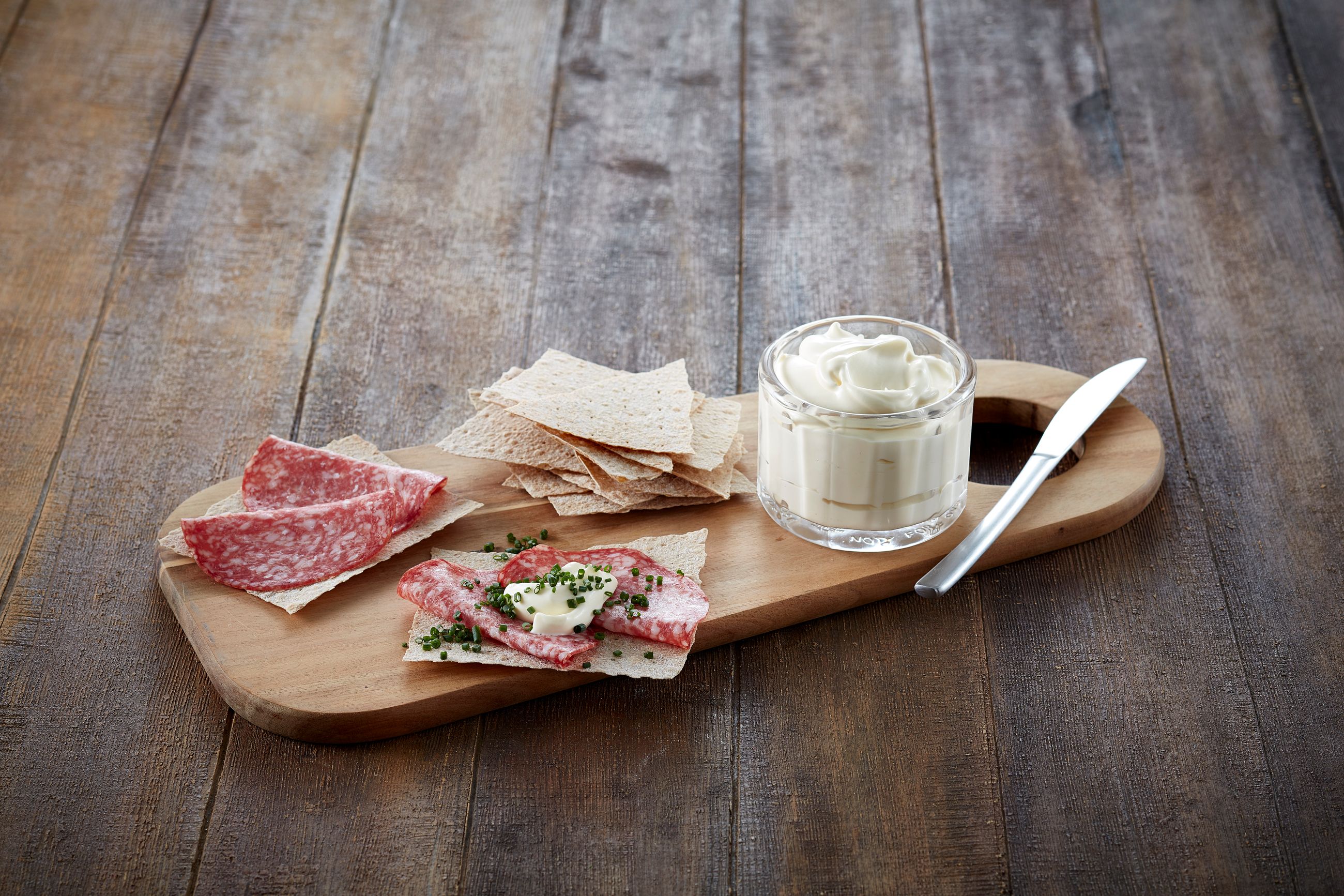 Fjøl med litt flatbrø og spekepølse på, og et glass med setterrømme