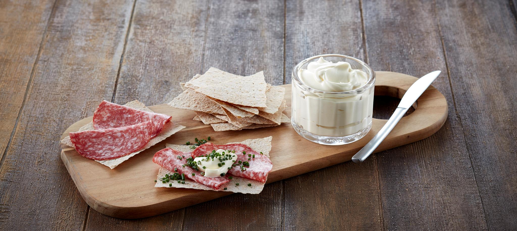 Fjøl med litt flatbrø og spekepølse på, og et glass med setterrømme