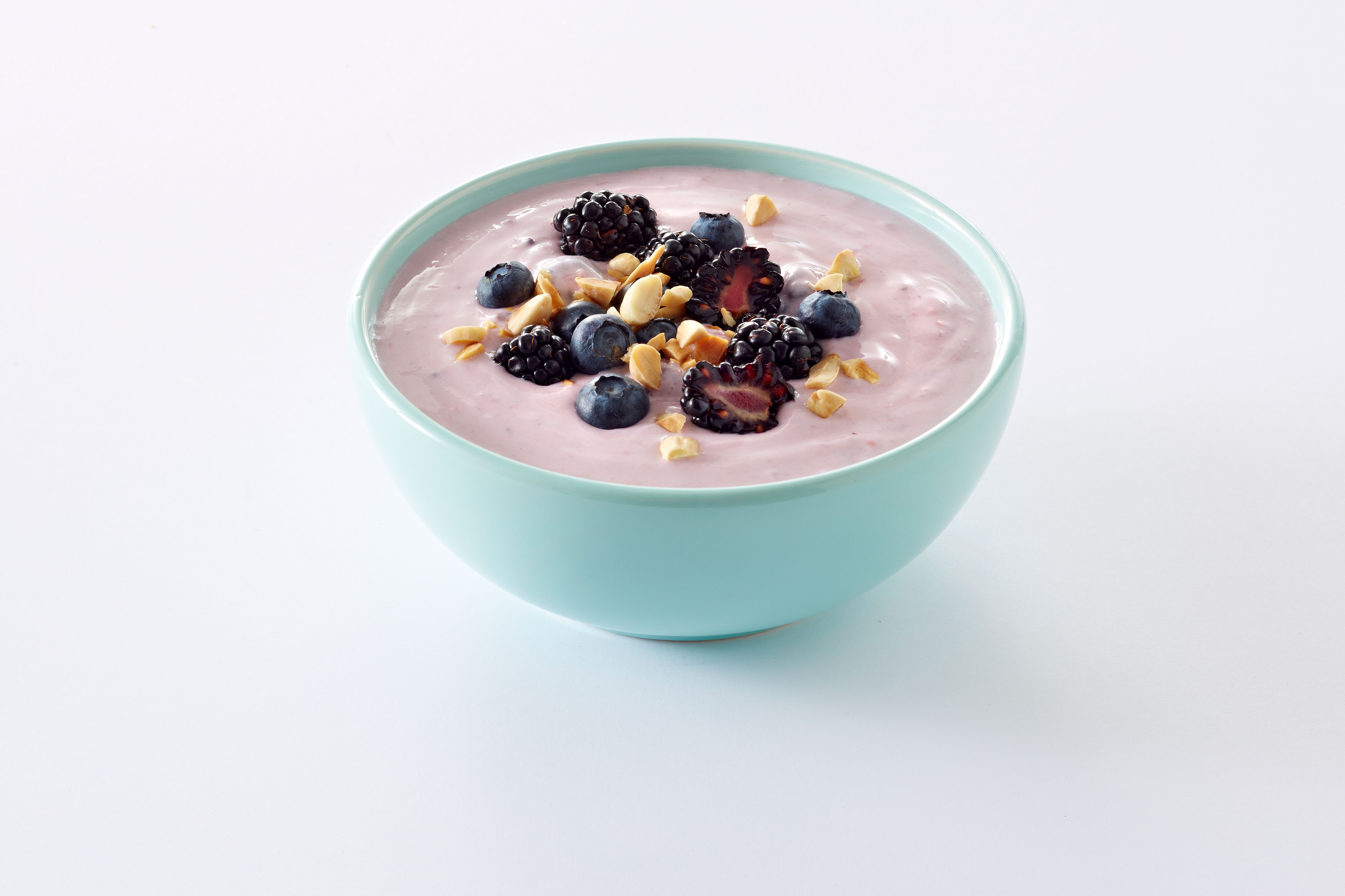 En turkis skål med yoghurt med bær og nøtter.