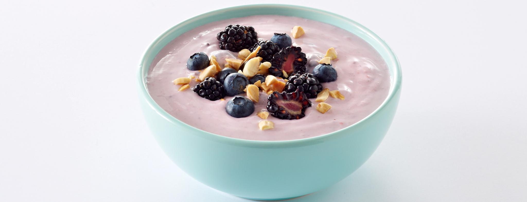 En turkis skål med yoghurt med bær og nøtter.