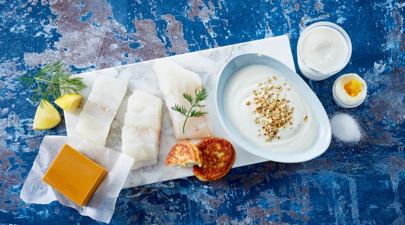 Blå benk med hvit marmorhelle med matvarer som er kilder til jod: Meieriprodukter, fisk, egg og salt