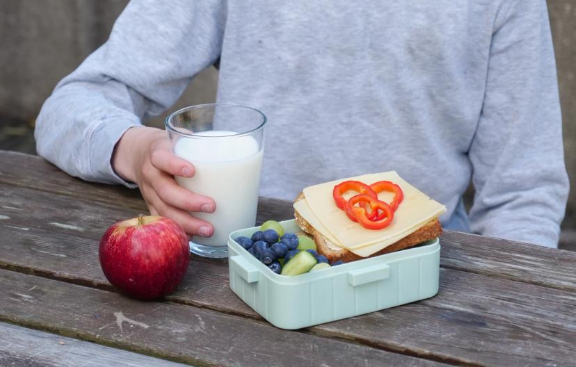 Barn i et lekestativ med svarte tavler med budskap om matpakke