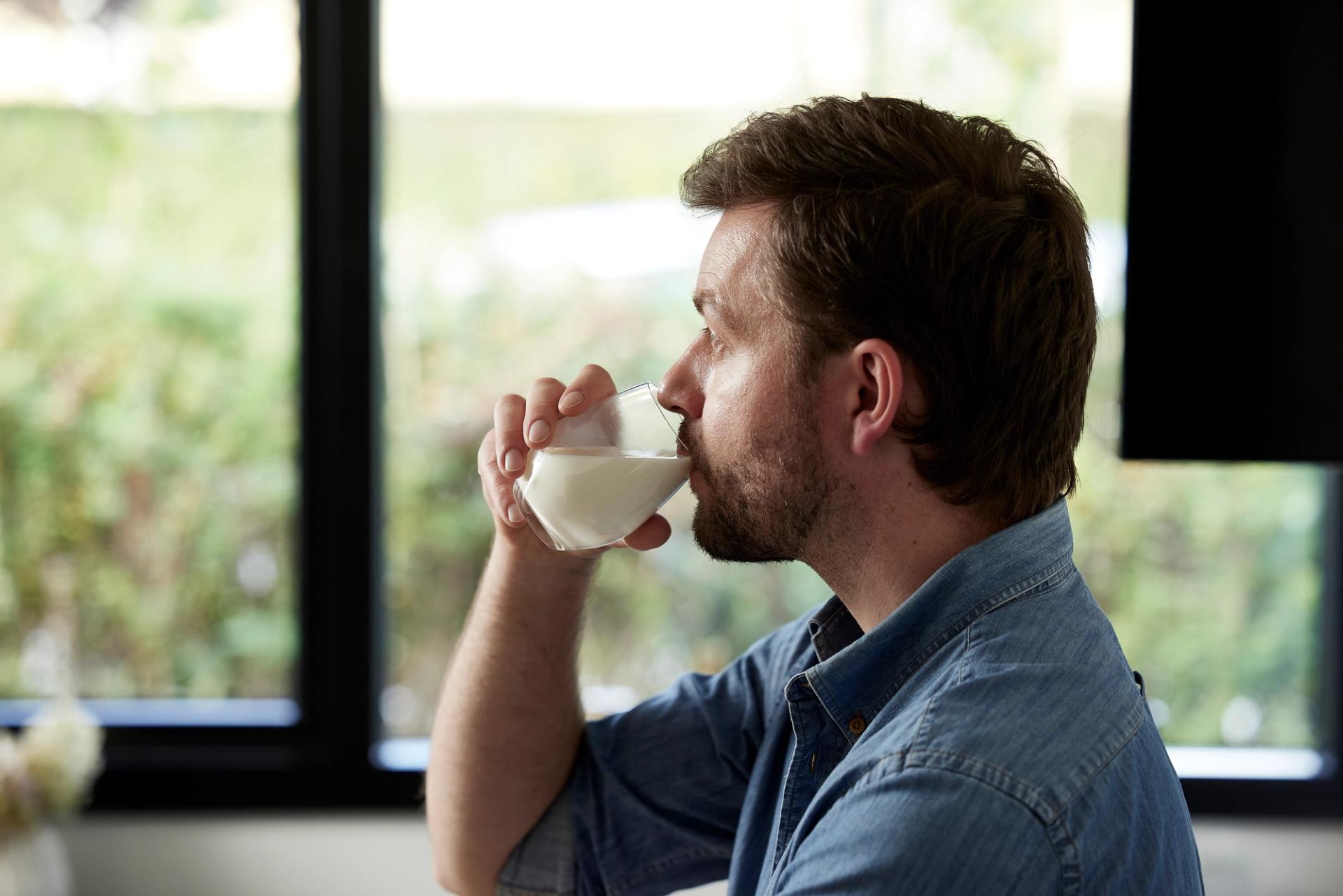 Mann i blå skjorte som drikker melk