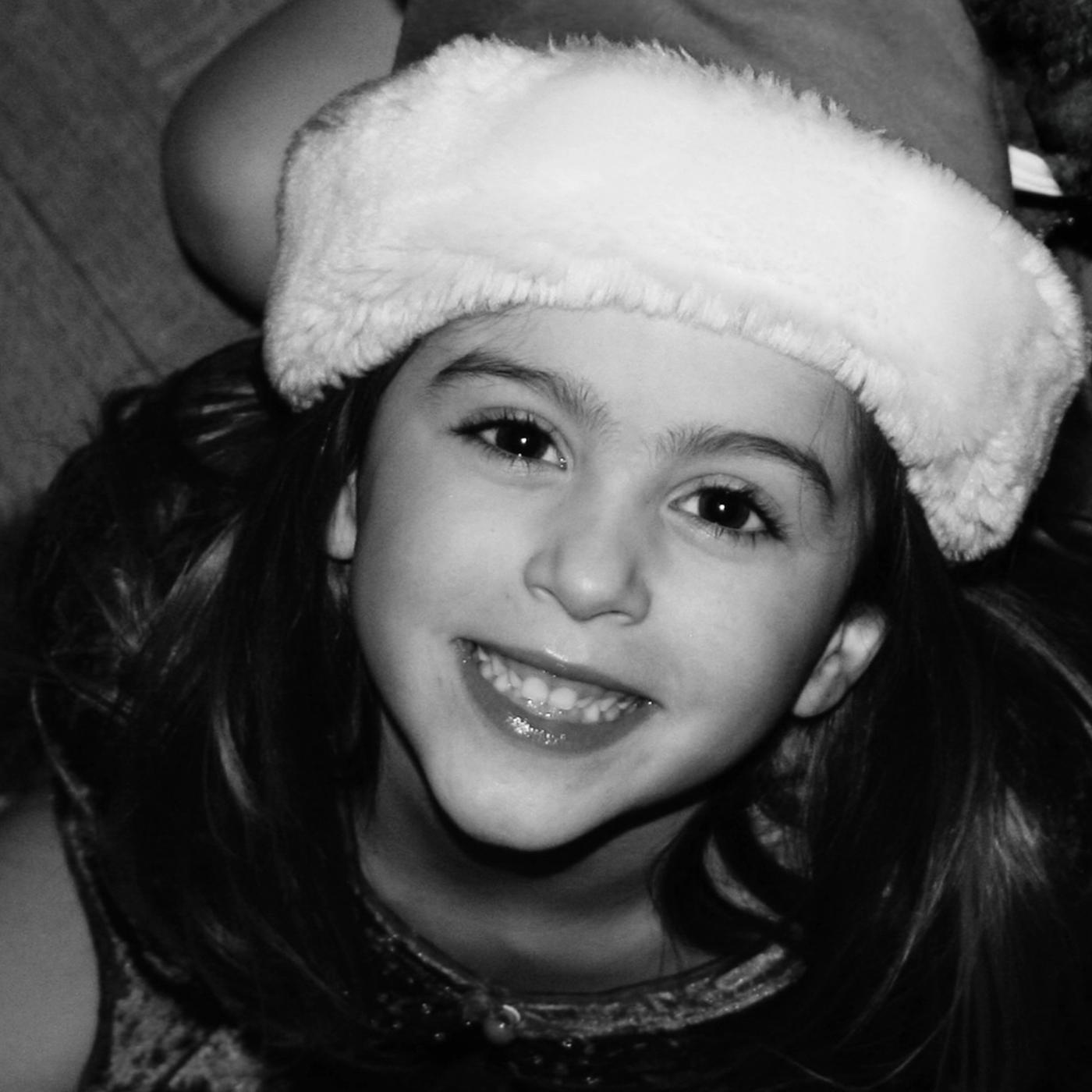 Single artwork for Ally Salort's Last Christmas, a black and white photo of a smiling young girl in a Santa hat
