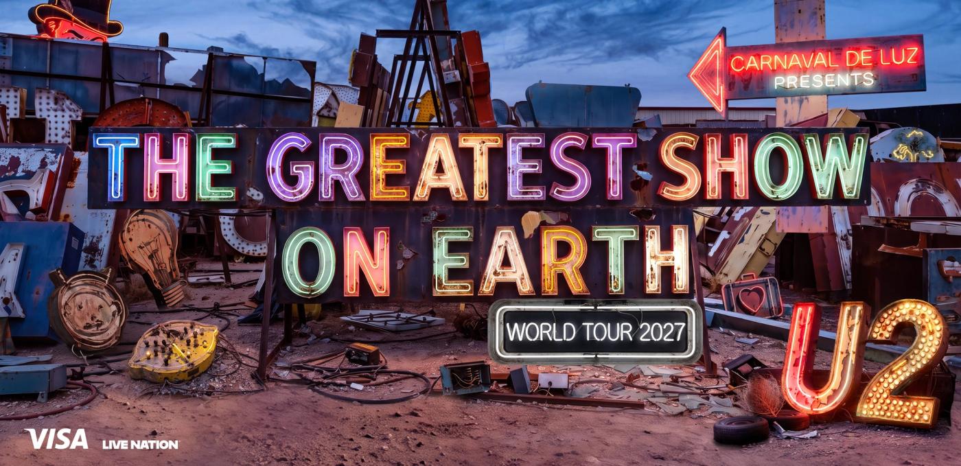 Neon signs reading The Greatest Show On Earth, World Tour 2027, Carnaval De Luz Presents and U2 in a desert sign graveyard, with Visa and Live Nation logos