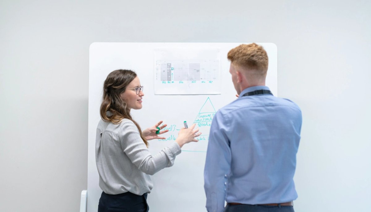 One person describe an idea to the other person near the whiteboard. 