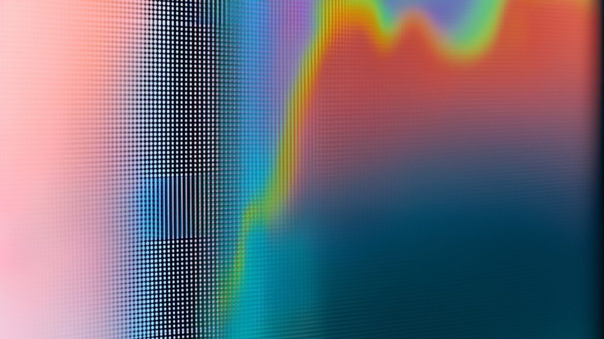 Abstract close-up of a digital screen showing a colorful pixelated wave pattern in orange, blue, and pink, representing data and artificial intelligence technology.
