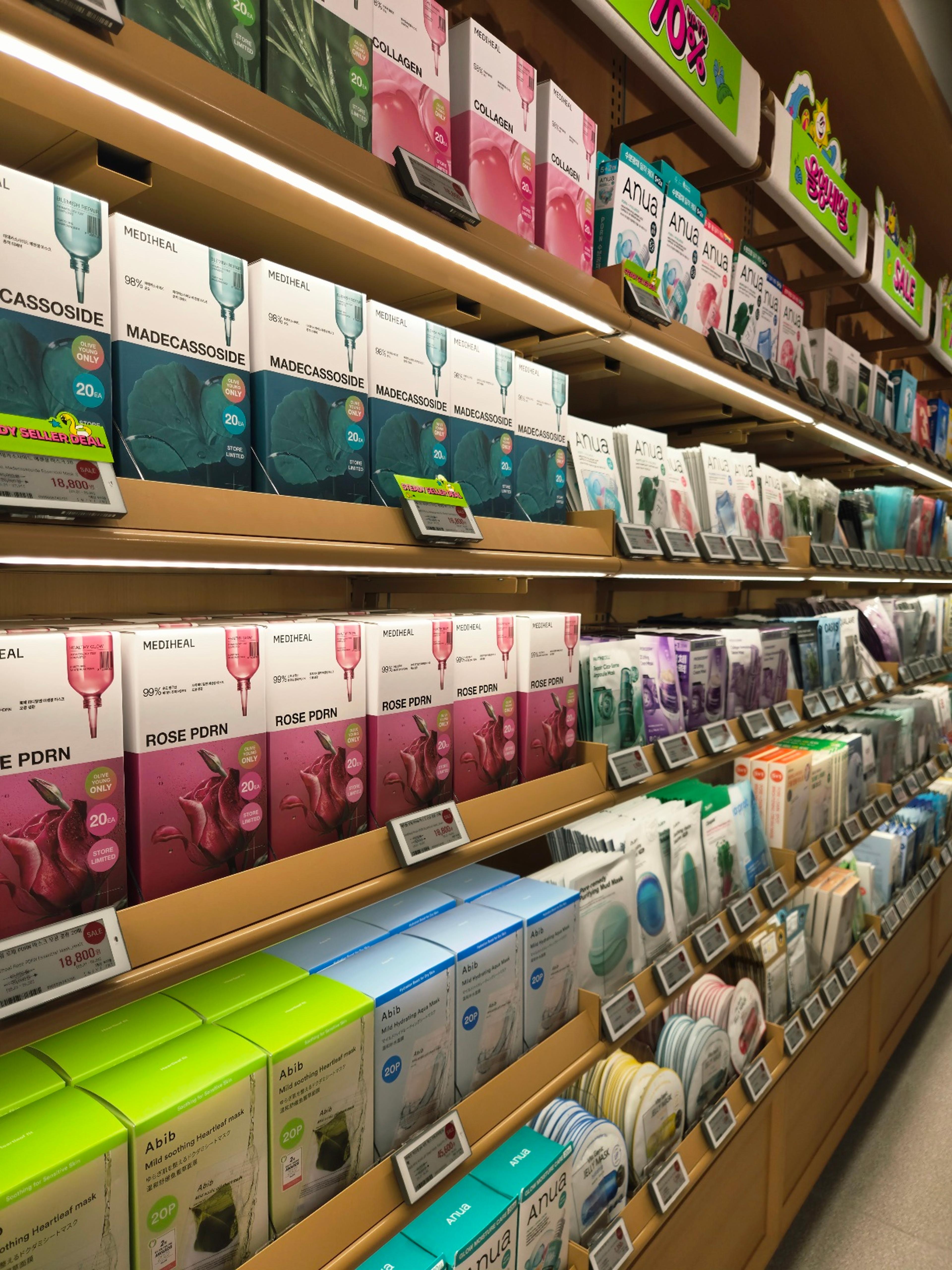 Brightly lit wooden shelves packed with colorful boxes of Mediheal, Anua, and Abib sheet masks on sale.