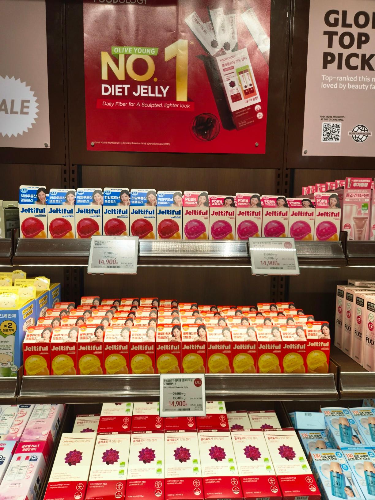 Shelves stocked with bright pink and yellow boxes of Jeltiful and Foodology diet jelly sticks under a red promotional banner.