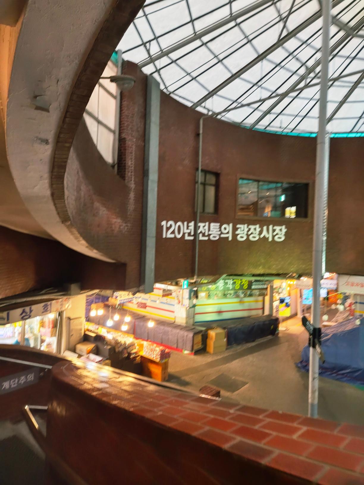 A historic round brick dome ceiling inside Gwangjang Market with a sign celebrating its 120-year tradition.