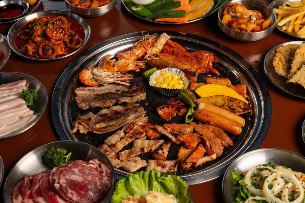 Top-down image of Korean barbecue table with grilled pork belly, kimchi, vegetables