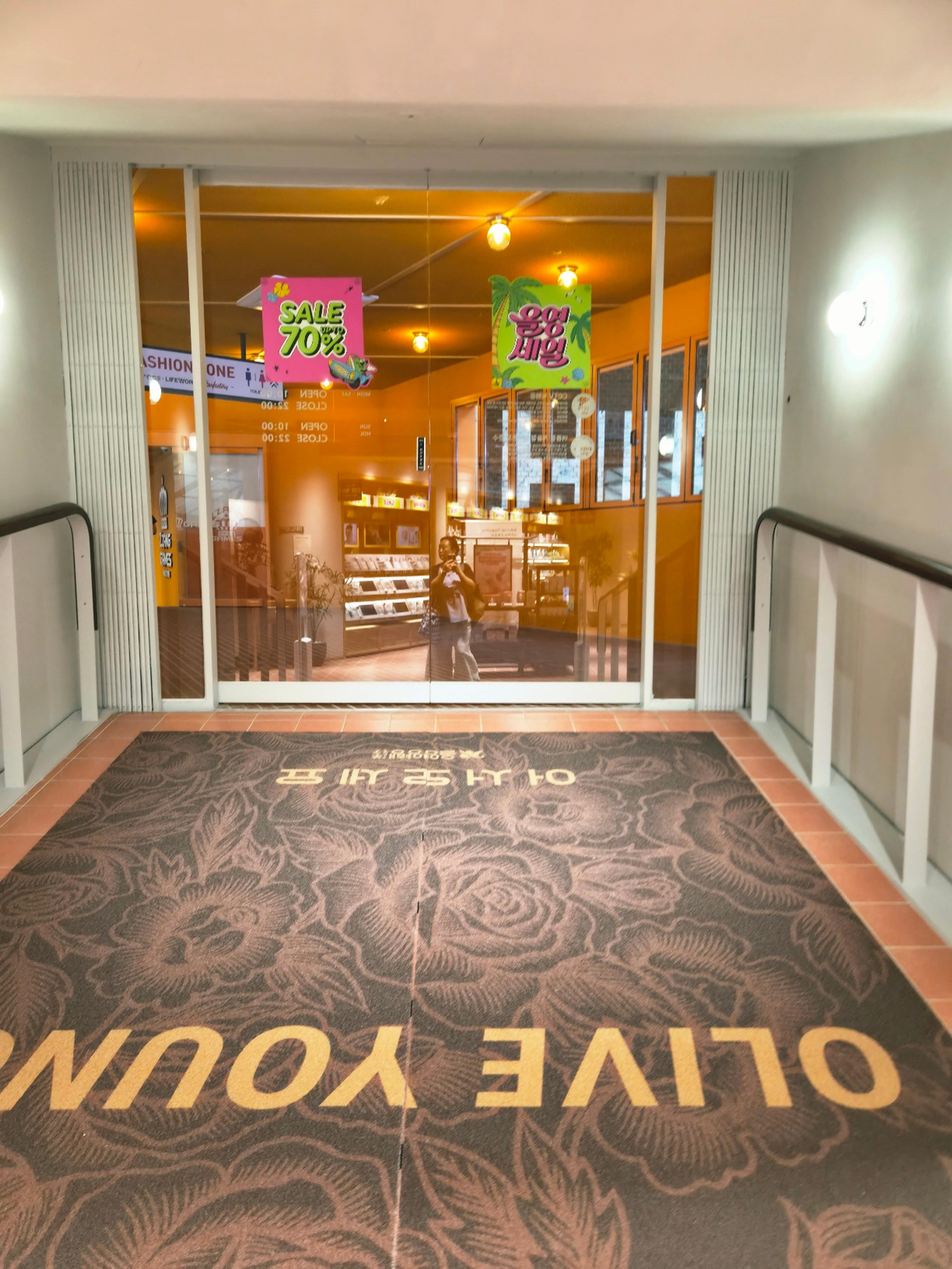 A premium brown floor mat with elegant rose patterns and gold Olive Young lettering at the store exit.