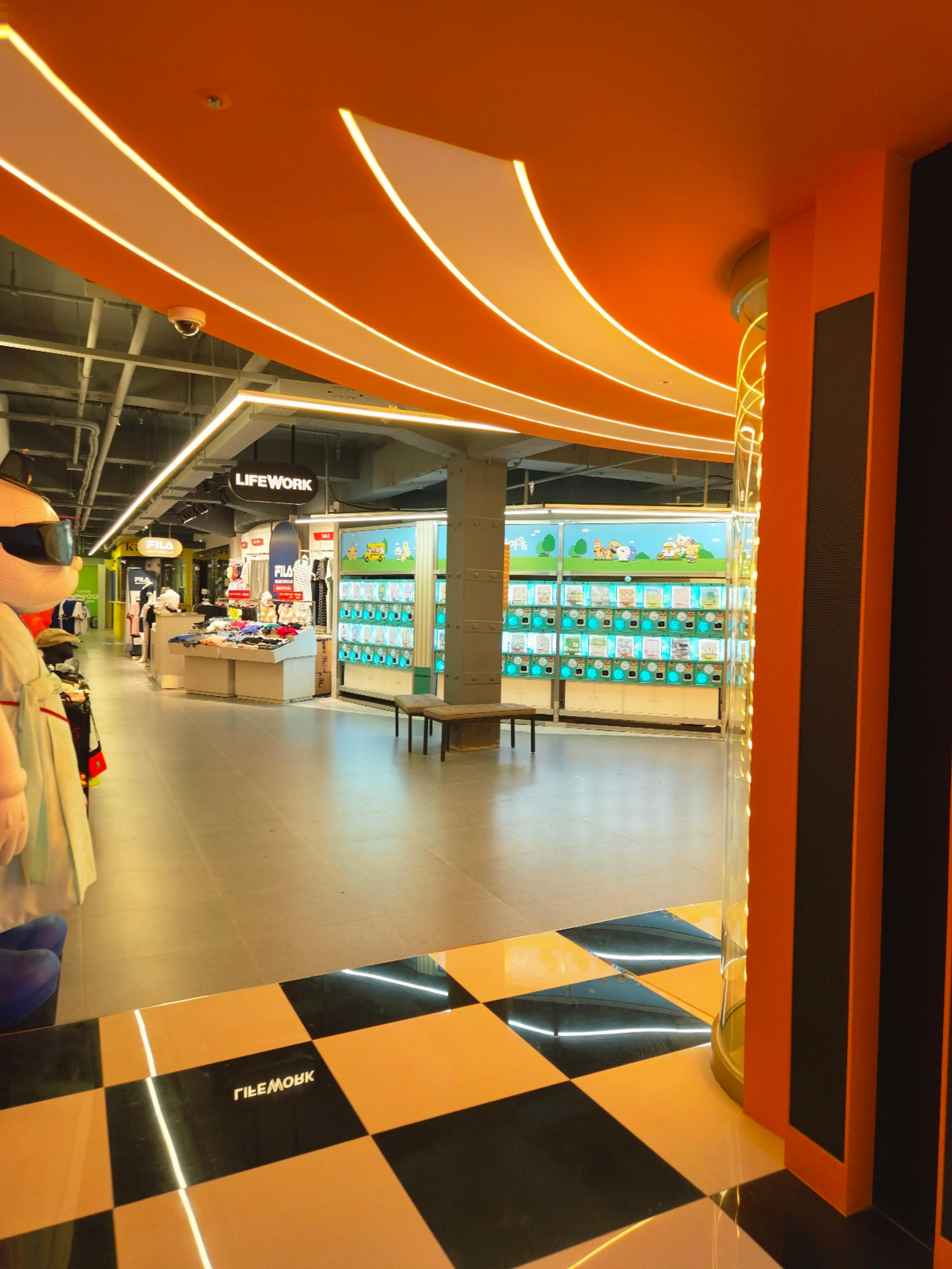 A modern retail space featuring a bold black and white checkered floor and walls lined with capsule toy gachapon machines.