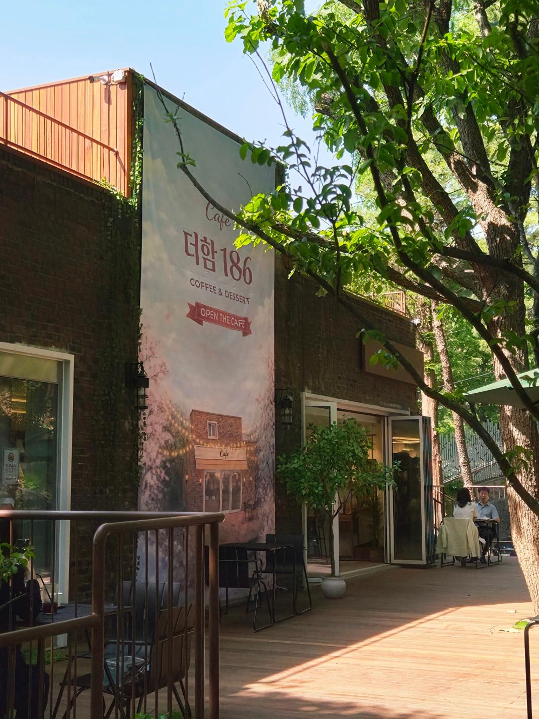Weathered brick exterior of Cafe Theham 186 nestled perfectly under large, leafy trees