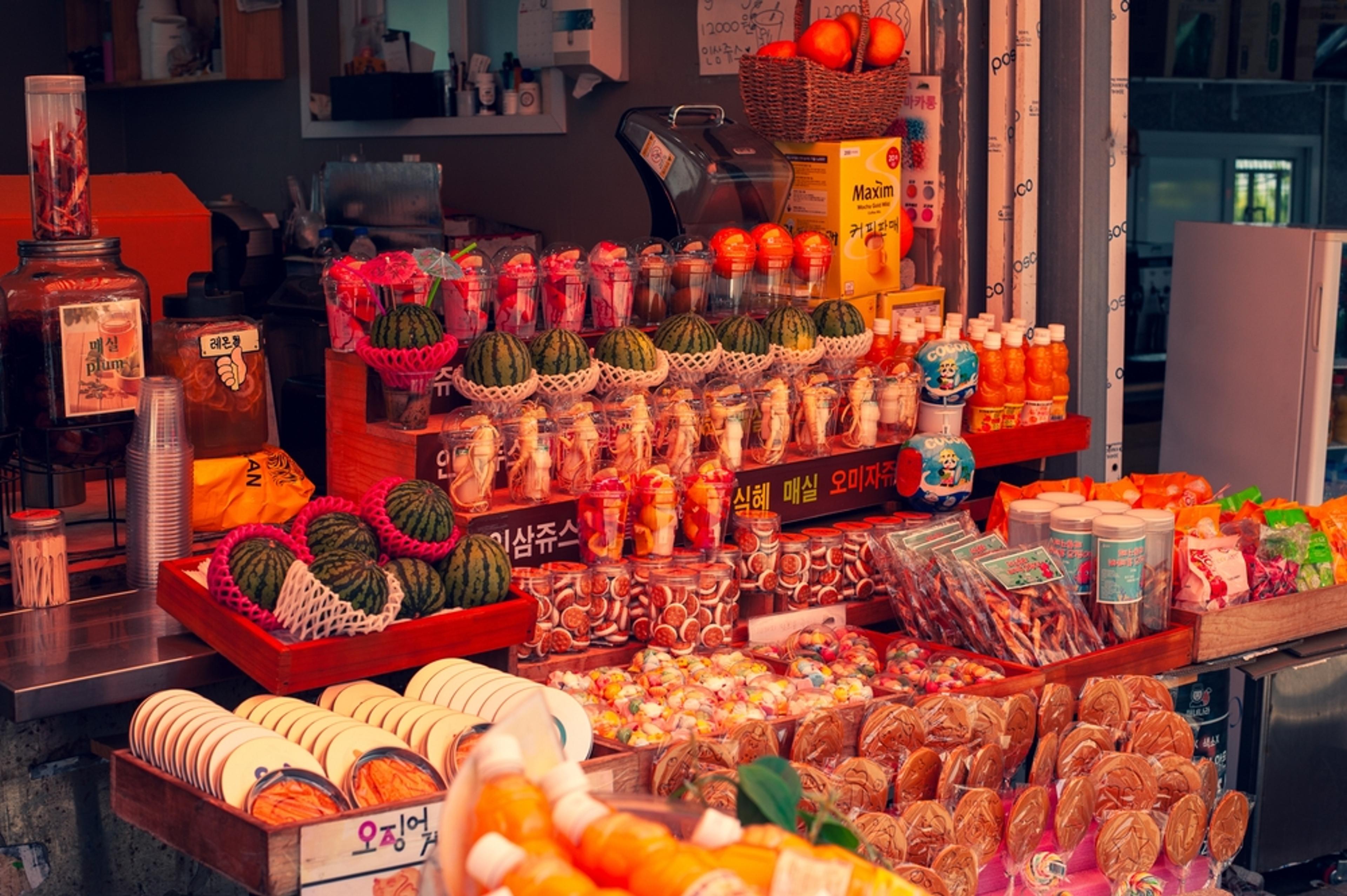 A vibrant street market stall filled with colorful snacks and fruit juices on a summer day