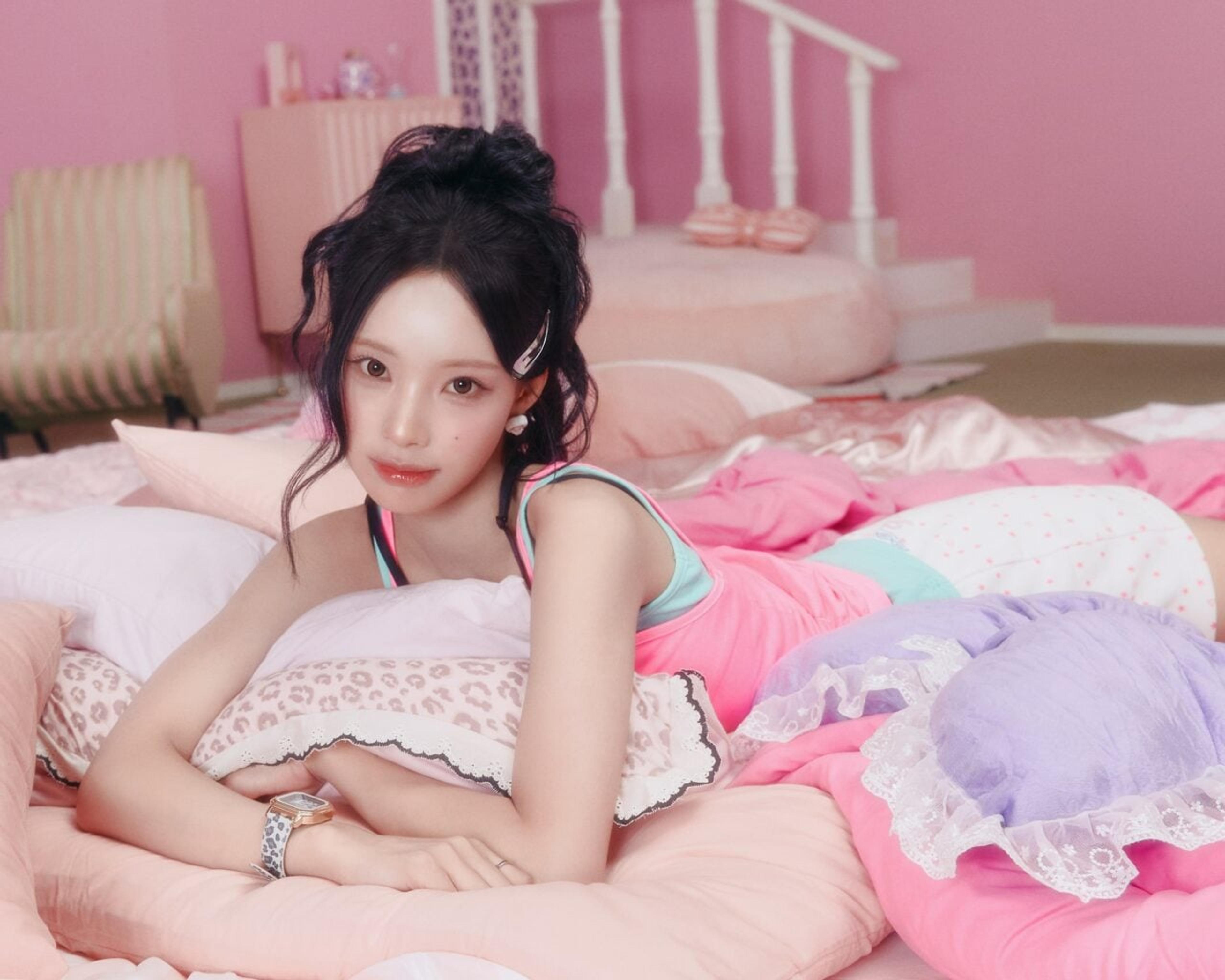 Woni of RESCENE lying on pastel pillows in an official pink-themed promotional portrait