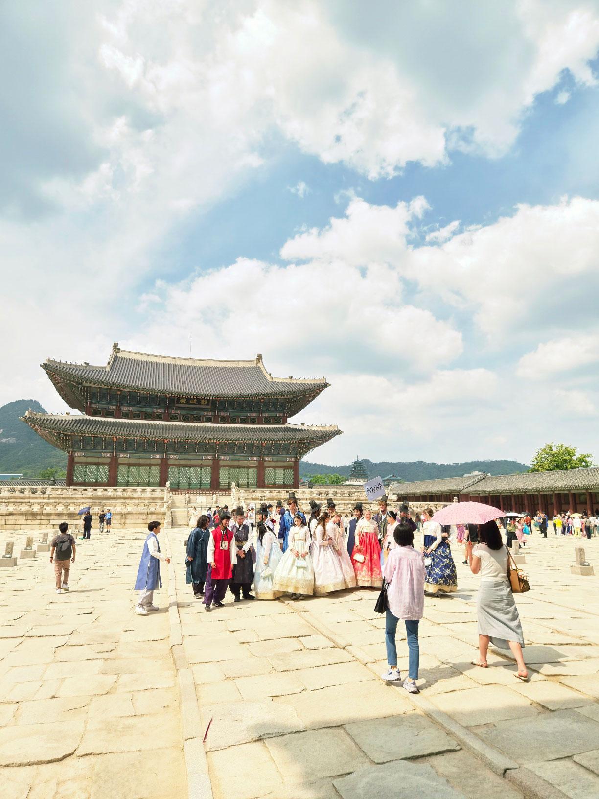 Geunjeongjeon throne hall from the courtyard — the one with hanbok-wearing tourists in front