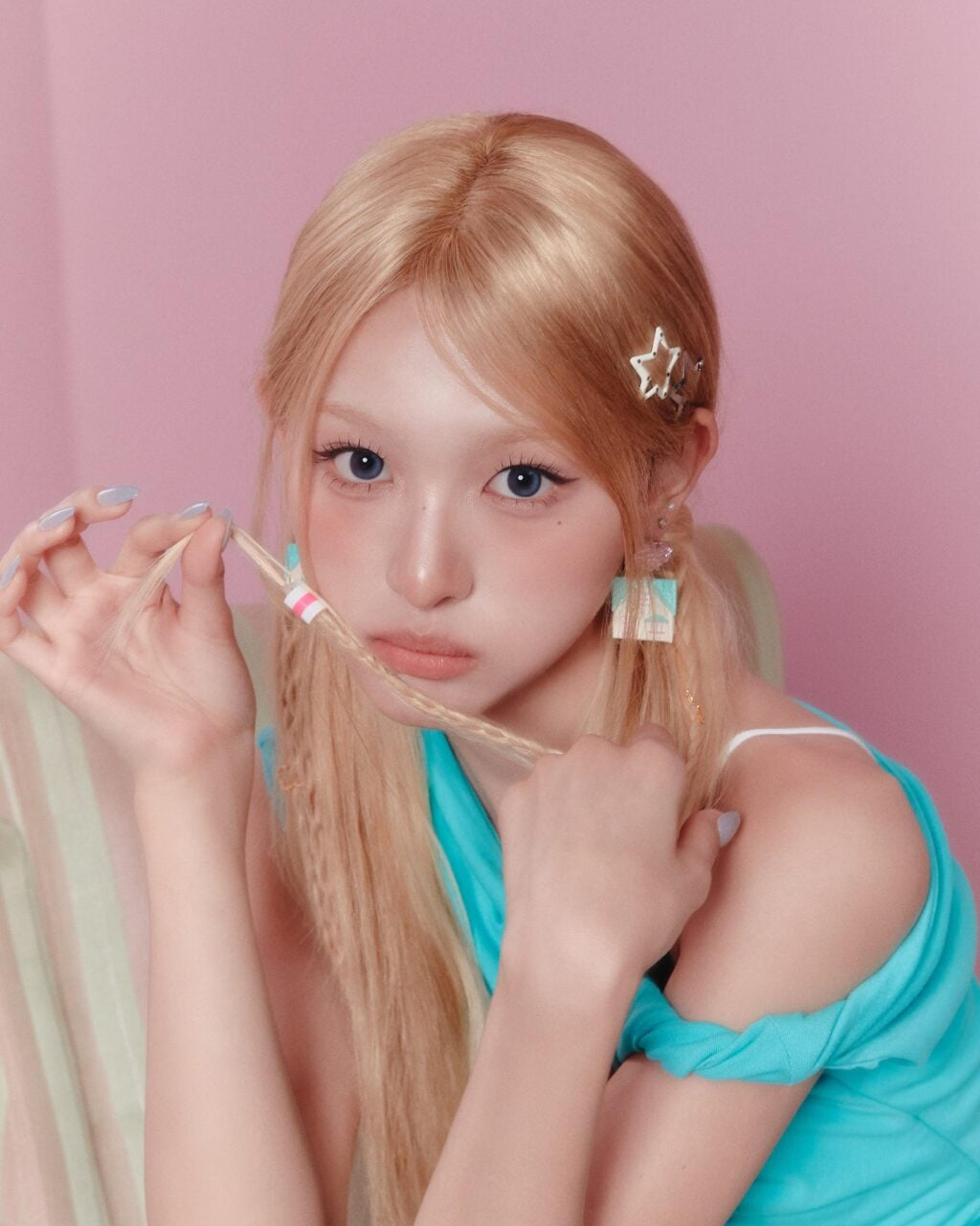 Minami of RESCENE wearing a turquoise outfit in an official pink-themed promotional portrait
