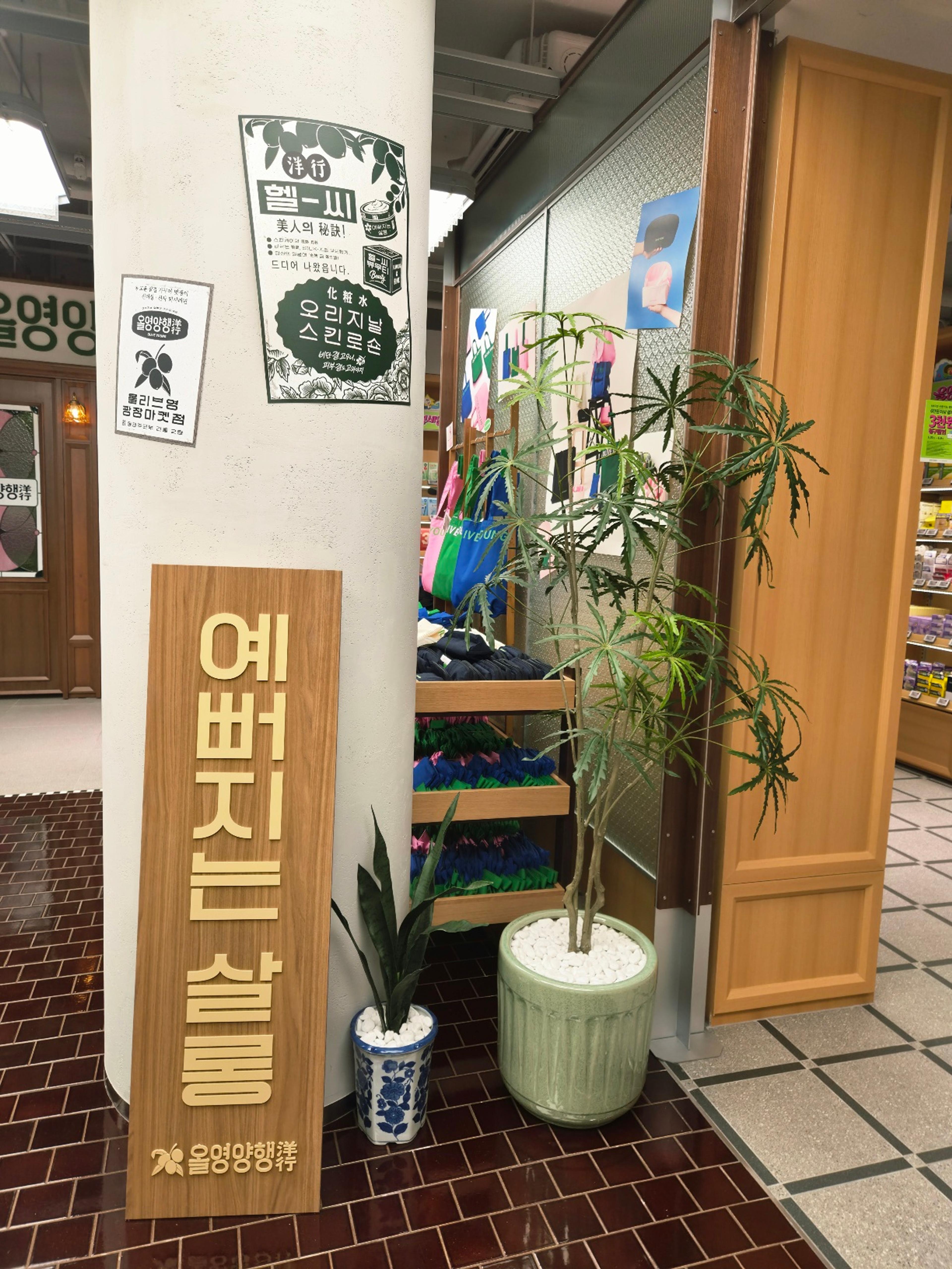 A structural column inside the store decorated with vintage prints next to a wooden sign and green potted plants.
