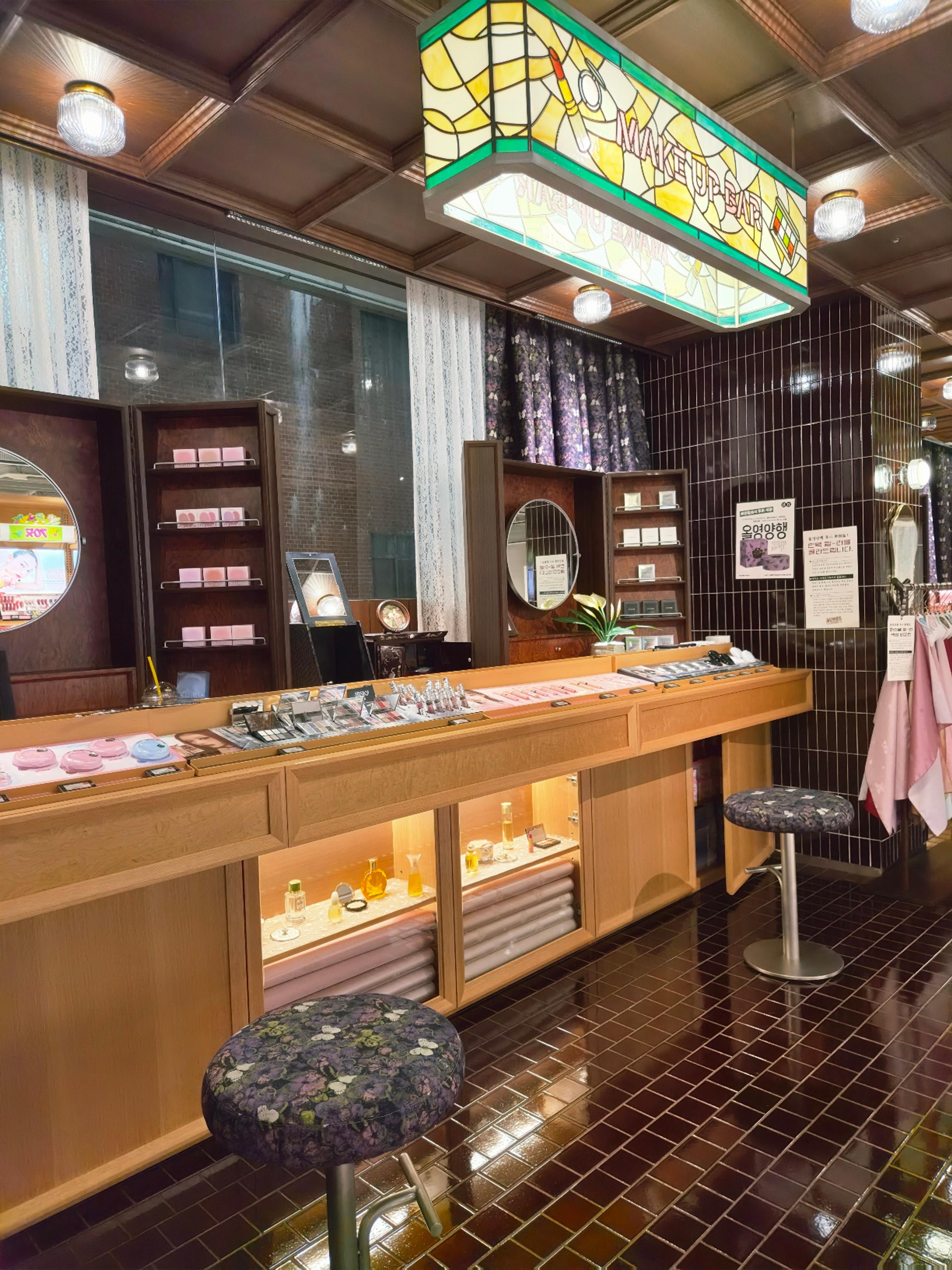 A premium makeup testing counter featuring an exquisite retro stained glass overhead sign reading Makeup Bar.