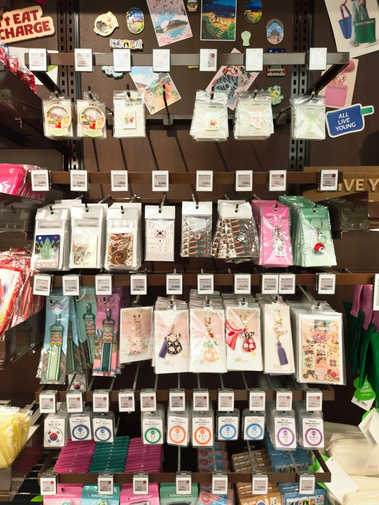 A close-up view of premium Korean souvenirs showing traditional dress keychains, colorful Seoul subway card holders, and decorative magnets.