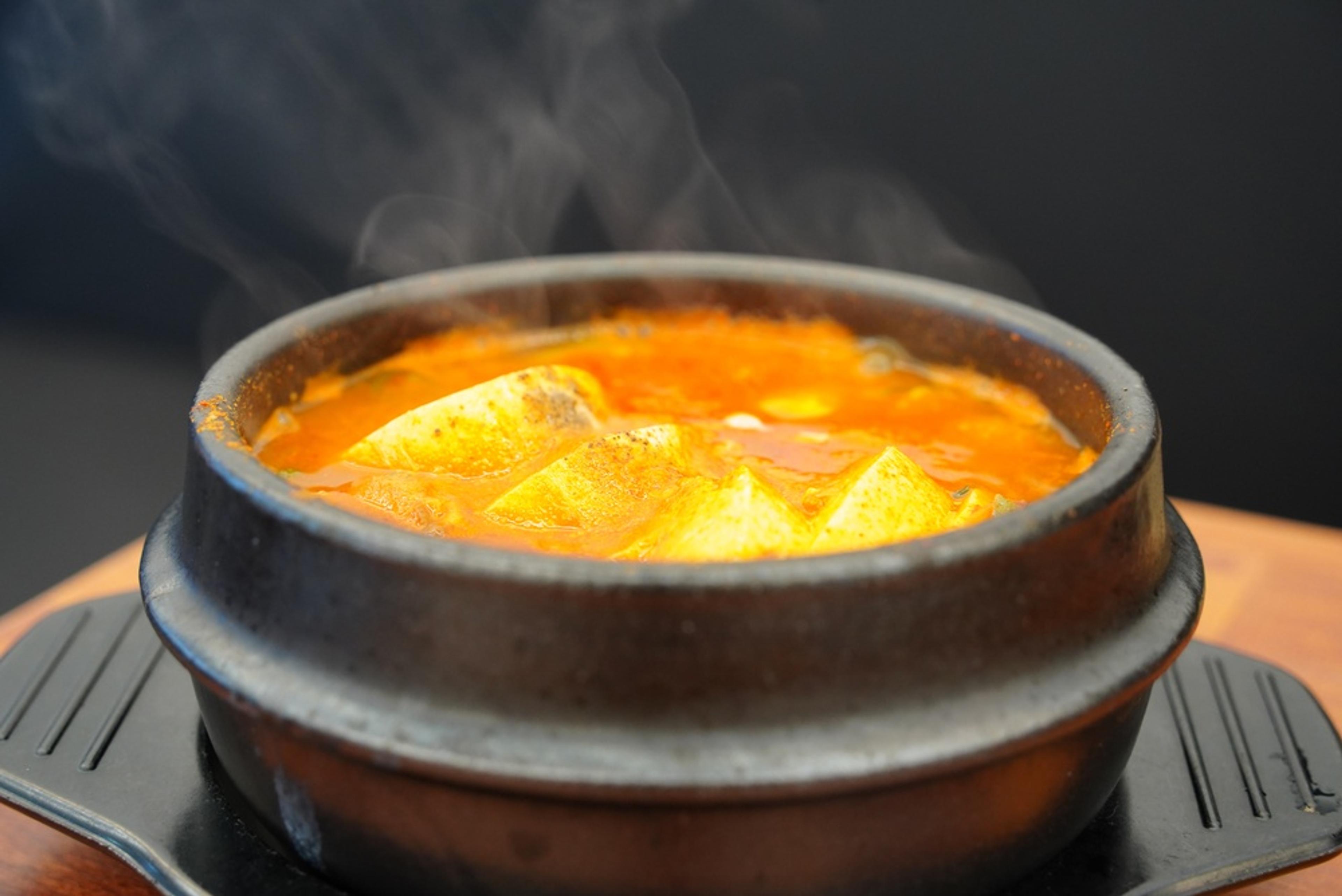 Steaming hot Korean spicy tofu stew (Sundubu-jjigae) served in a traditional earthenware pot