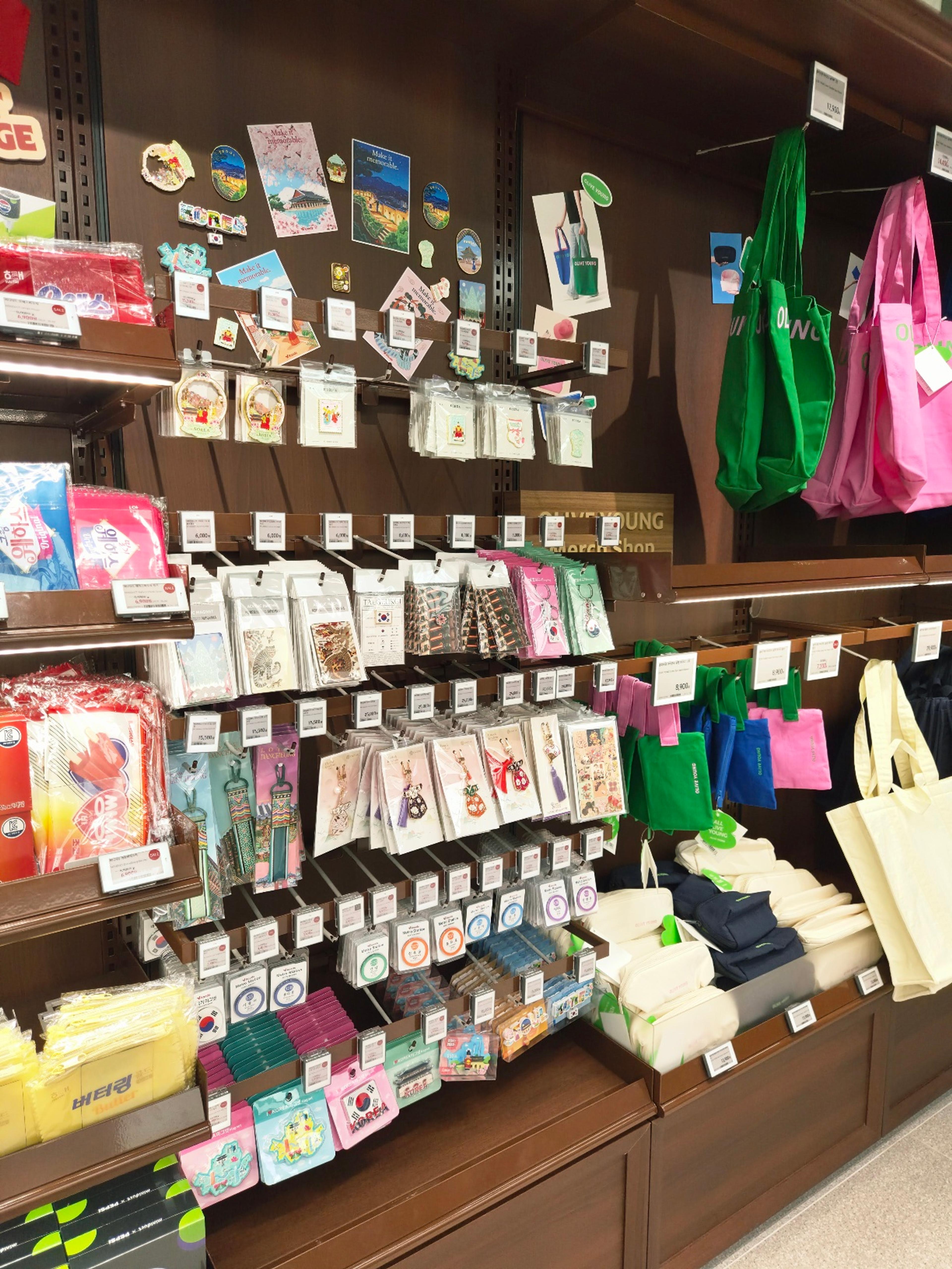 A dedicated merchandising wall filled with Korea-themed souvenirs including traditional postcards, magnets, and colorful canvas bags.