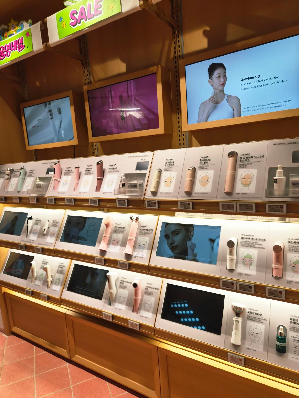 An interactive display wall lined with premium high-tech Korean skincare devices and digital tutorial screens.