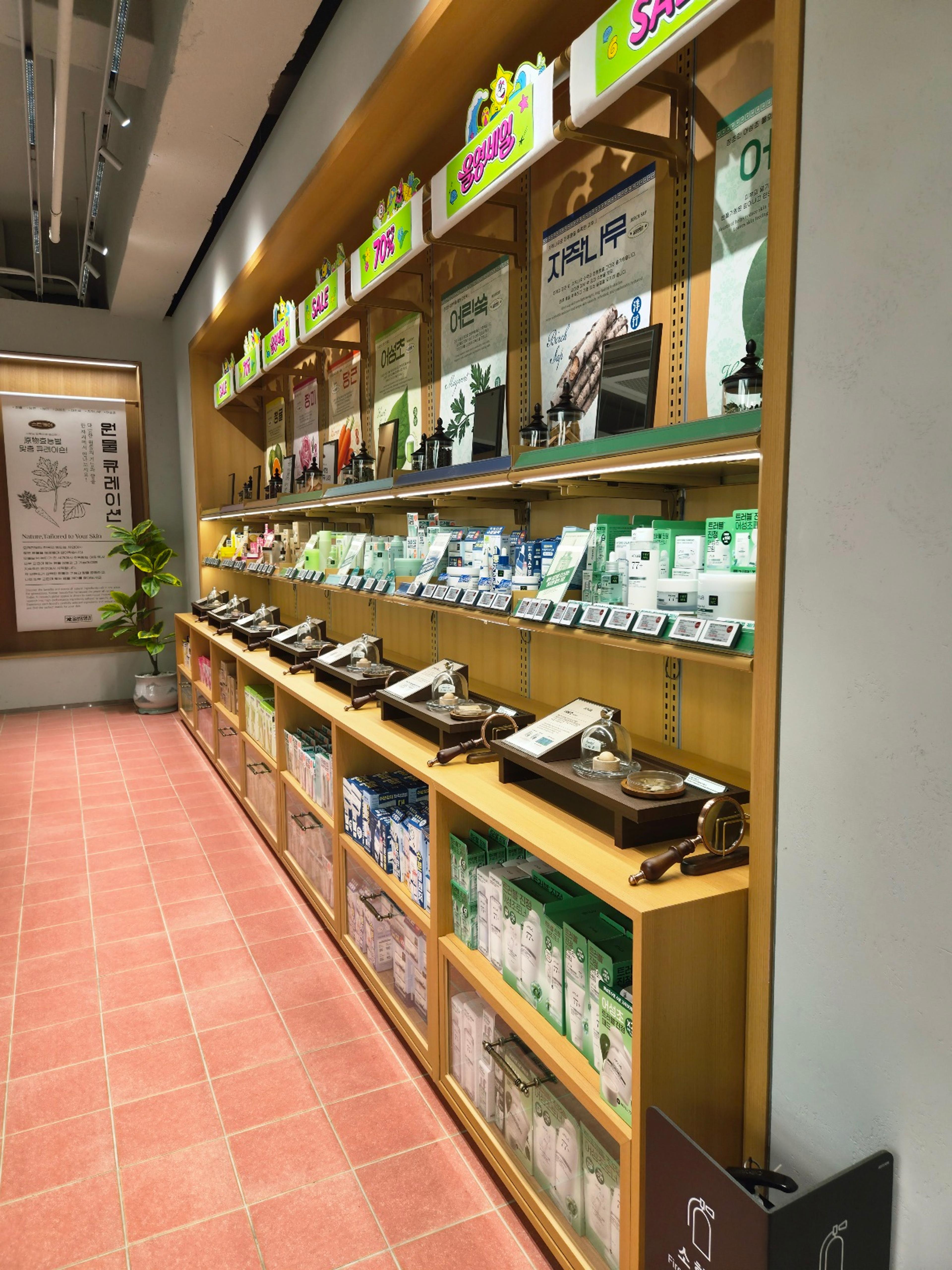A massive wooden display wall showcasing skincare products categorized by natural raw ingredients under individual glass cloches.