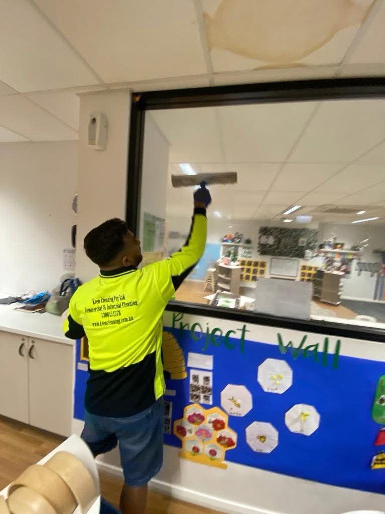 Keen Cleaning technician cleaning interior glass in a childcare classroom