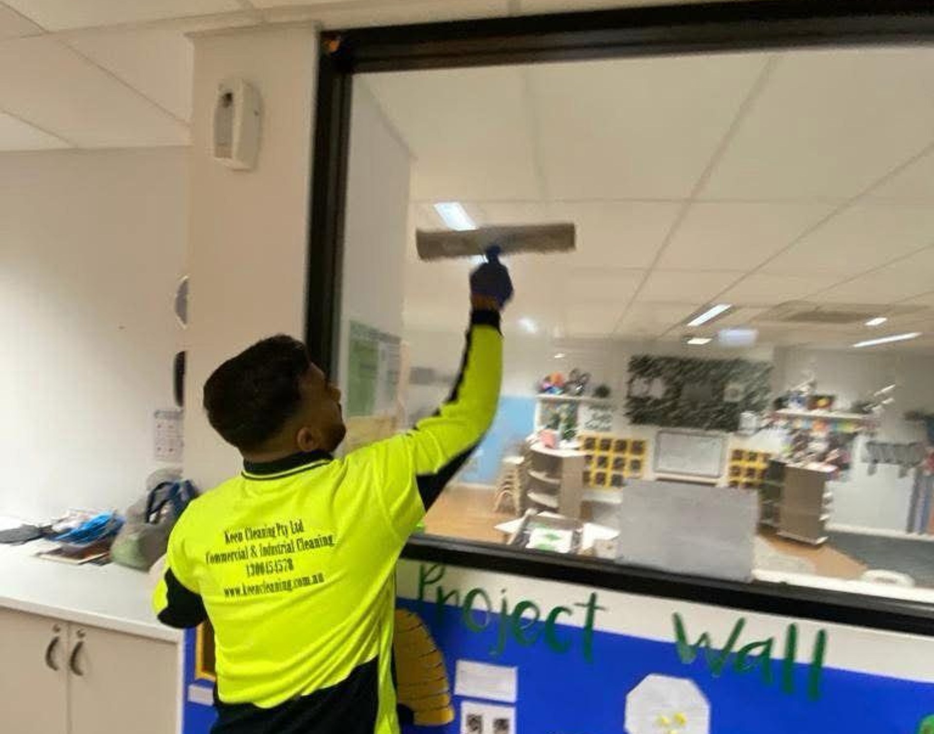 Keen Cleaning technician cleaning interior glass in a childcare classroom
