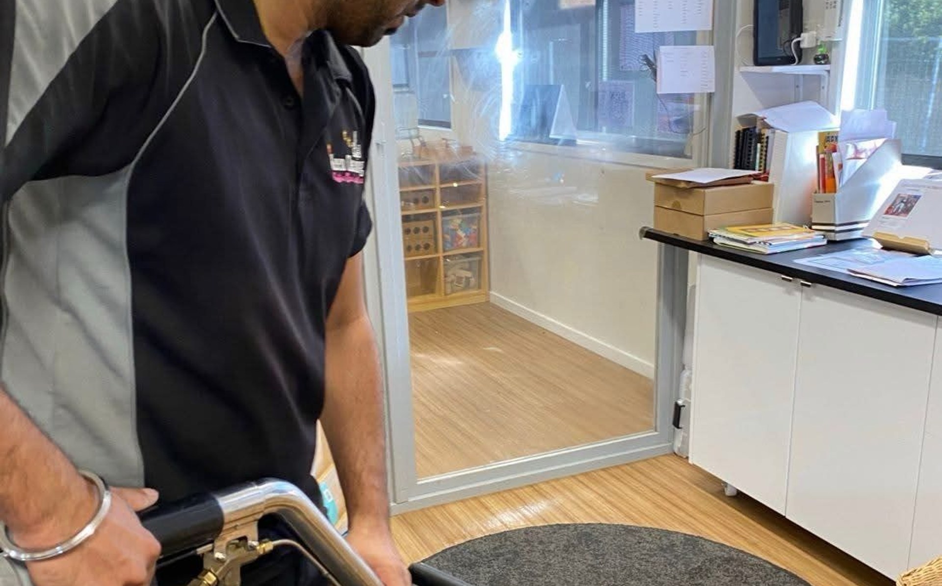Technician steam-cleaning a rug with a professional carpet wand