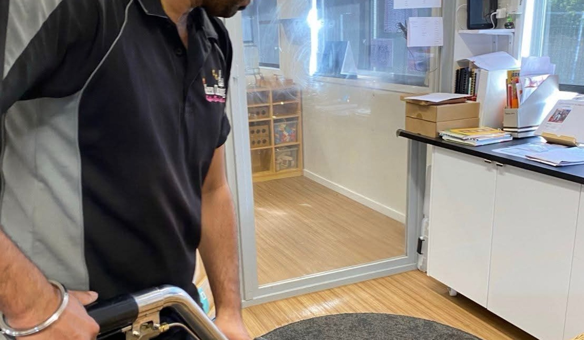 Technician steam-cleaning a rug with a professional carpet wand