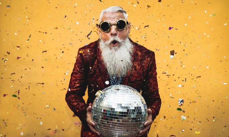 Energetic man in a party outfit holding a disco ball