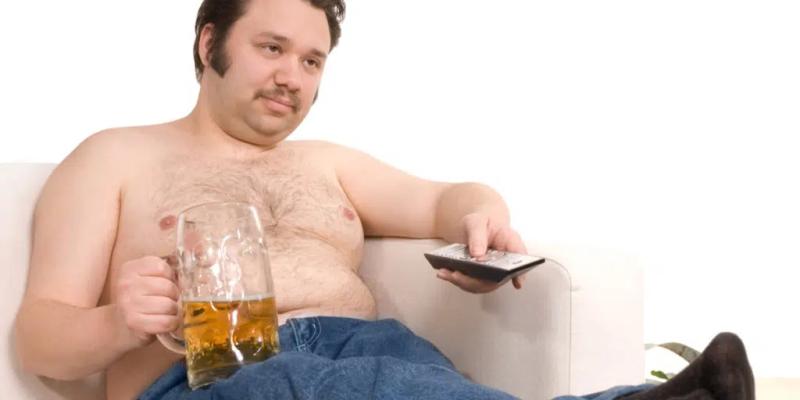 Overweight man drinking beer and watching tv.