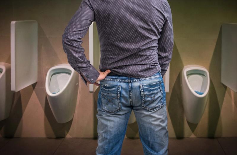 Mand som står ved et urinal og tisser