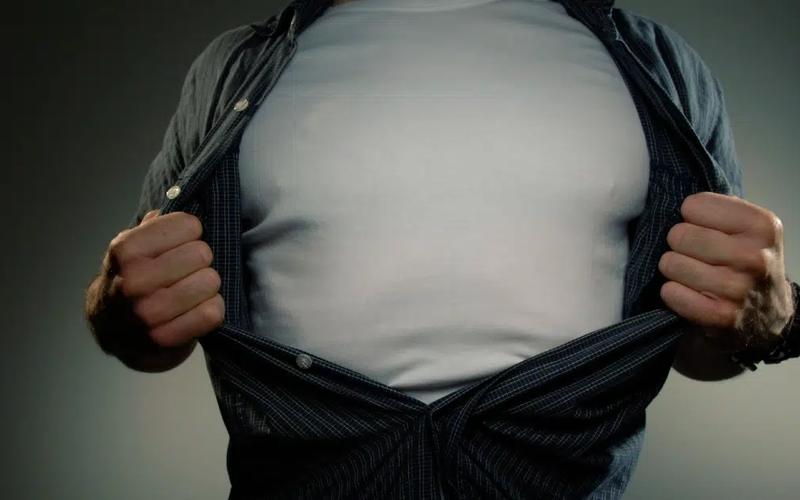 En man visar upp sin stora mage genom att dra skjortan åt sidan