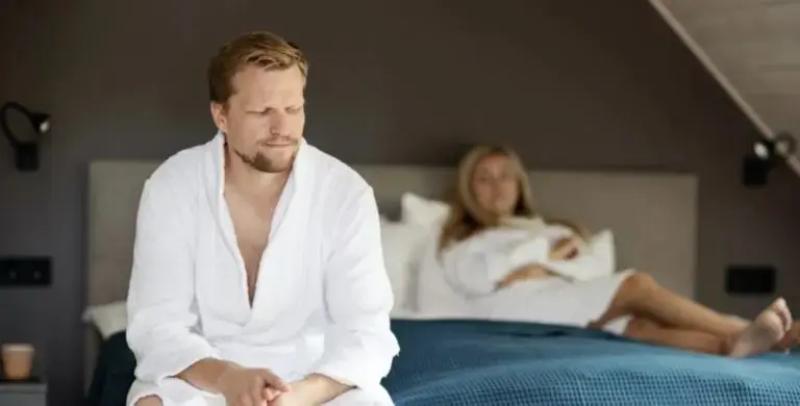 Mies istuu sängyllä naisen kanssa