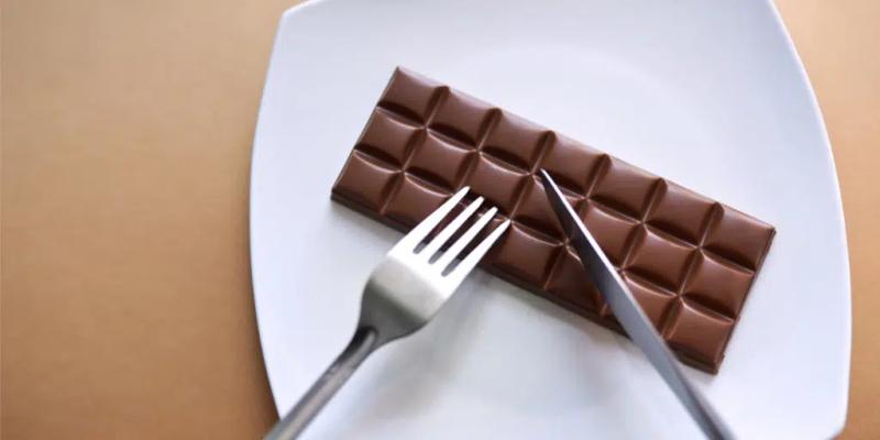 En chokladkaka som äts med kniv och gaffel på en middagstallrik