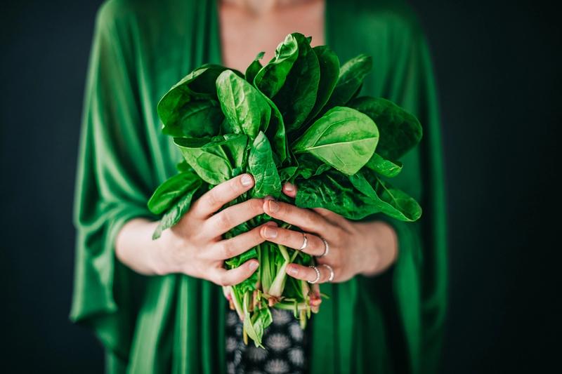 Woman in a green dress holding a bouquet of spinach