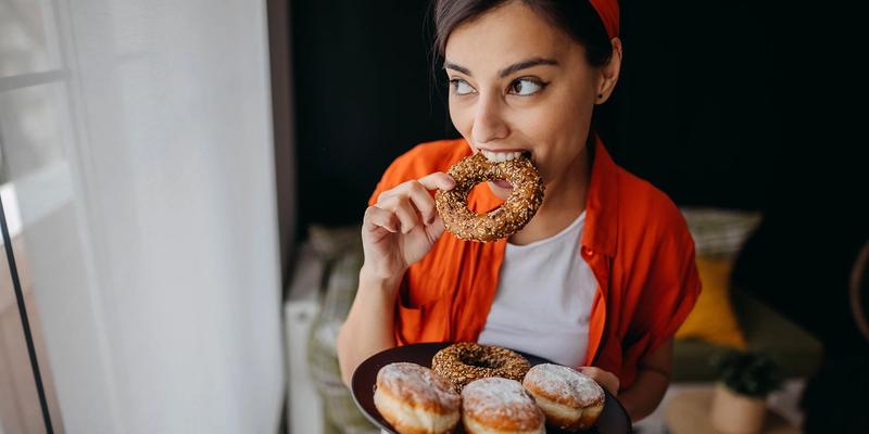 Kvinde med sukkertrang ved menstruation, der spiser donuts.