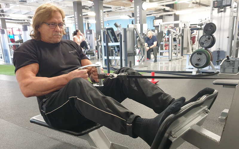 68-vuotias lihaksikas mies treenaamassa kuntosalilla voimaharjoittelua